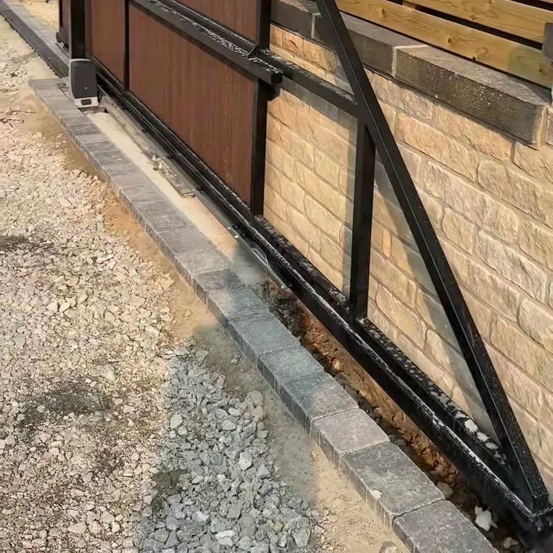 A new sliding electric gate on a stone driveway, motor fitted at the base